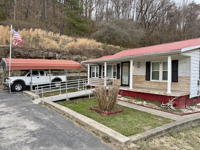 view of front of home with a porch, a detached carport, stone siding, and metal roof