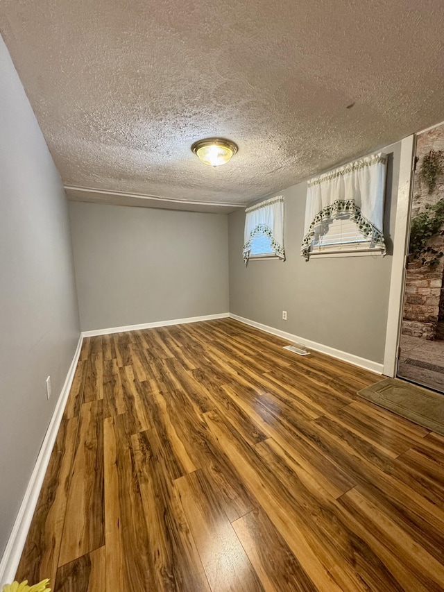 unfurnished room with baseboards, visible vents, and wood finished floors