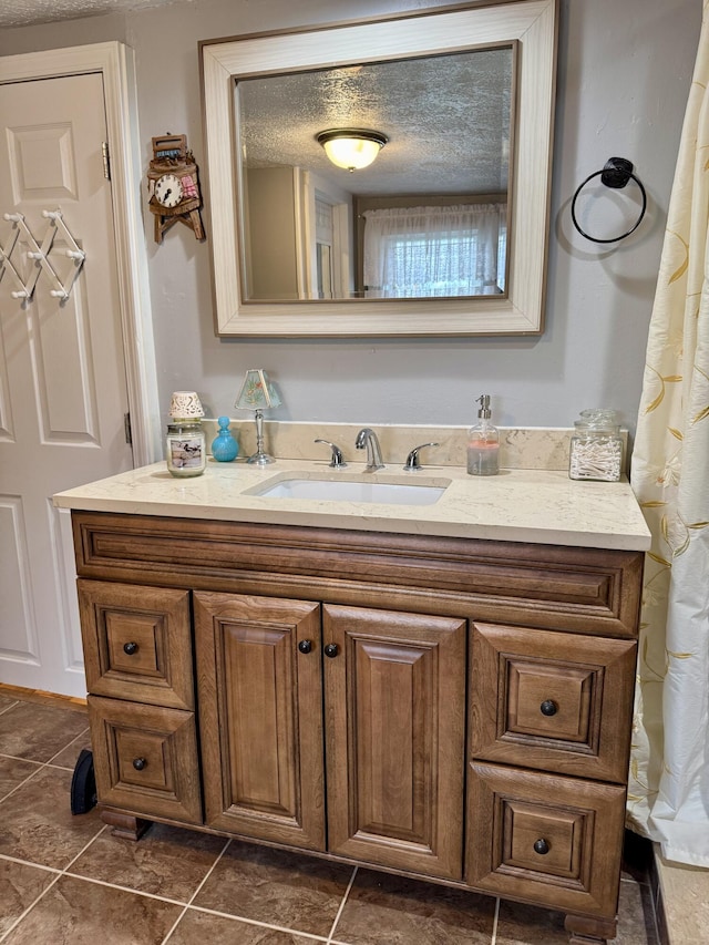 bathroom with tile patterned flooring, a textured ceiling, and vanity