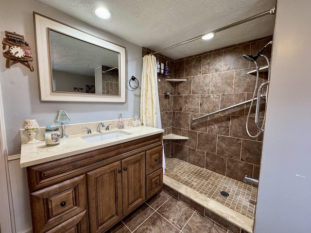 bathroom with recessed lighting, a textured ceiling, tiled shower, and vanity