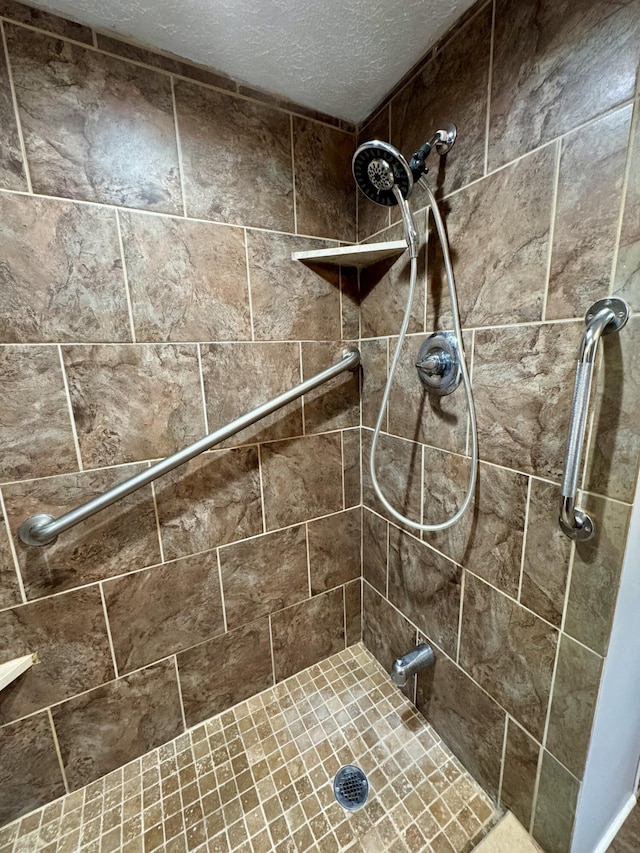 full bathroom featuring a textured ceiling and tiled shower