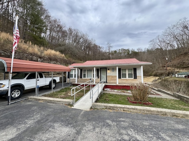 view of front of home featuring covered porch, metal roof, and a detached carport