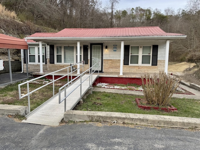 view of front of house with metal roof, stone siding, and a porch