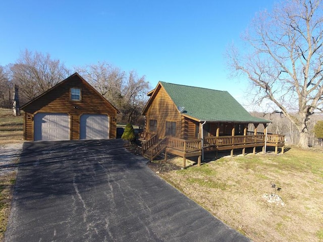 view of side of home featuring a garage, roof with shingles, log exterior, and an outdoor structure