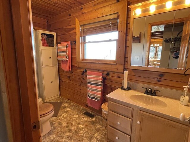 bathroom featuring wooden walls, visible vents, toilet, wooden ceiling, and vanity