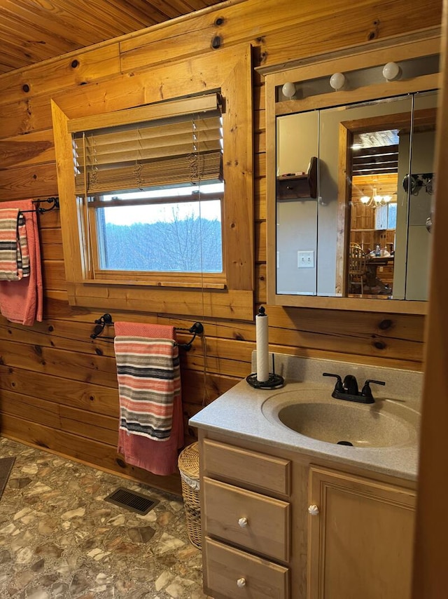 bathroom featuring stone finish floor, wooden walls, visible vents, and vanity