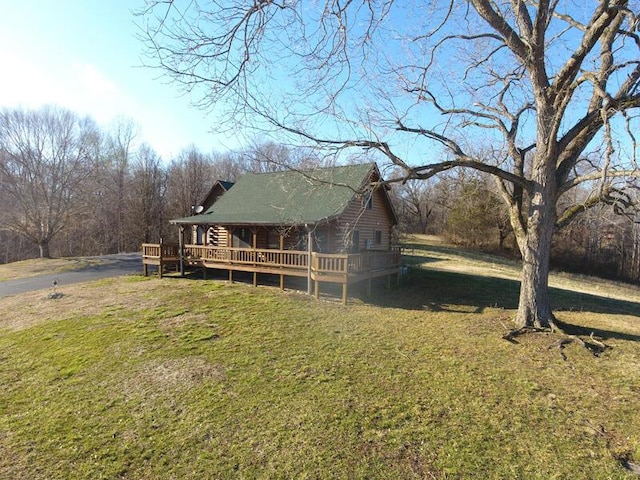 view of side of property with a yard, a wooden deck, and log siding