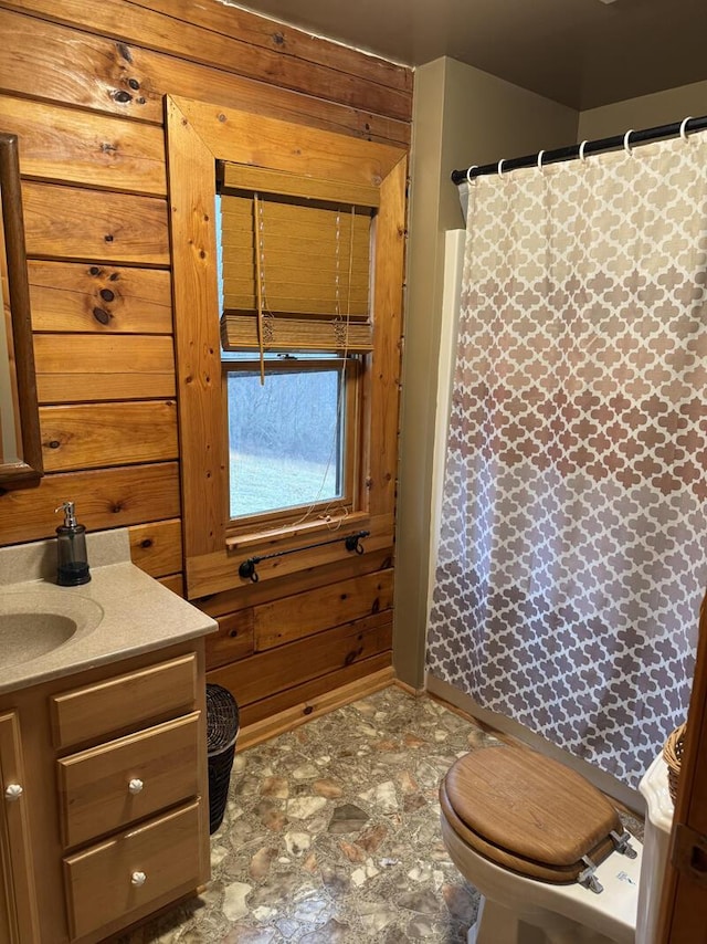 full bathroom with a shower with shower curtain, vanity, toilet, and wooden walls