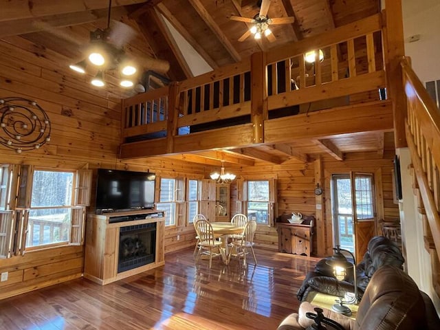 living area featuring plenty of natural light, wood finished floors, beam ceiling, and wooden walls