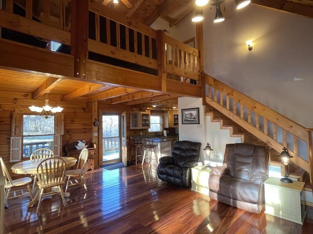 living area featuring an inviting chandelier, wood walls, wood finished floors, beamed ceiling, and stairs