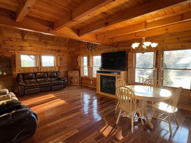 living room featuring a healthy amount of sunlight, an inviting chandelier, wood finished floors, and wooden walls