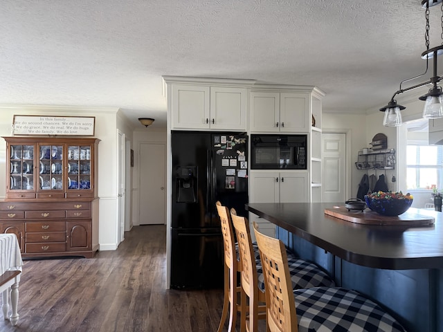 kitchen featuring dark wood finished floors, black appliances, dark countertops, and ornamental molding