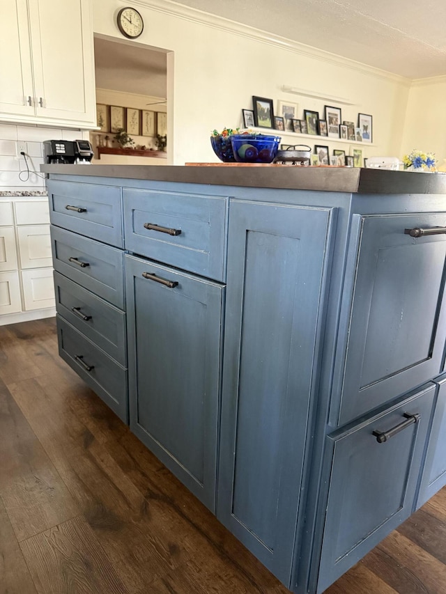 interior space with ornamental molding, decorative backsplash, white cabinets, blue cabinets, and dark wood-style flooring