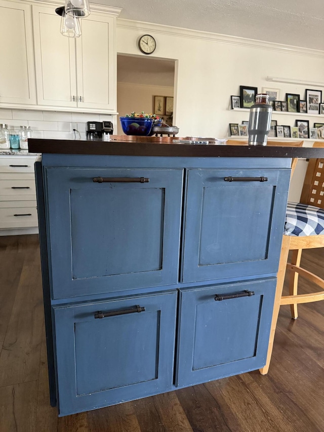 details featuring dark countertops, blue cabinetry, dark wood-style flooring, and ornamental molding