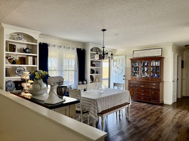 dining area with a textured ceiling, dark wood-type flooring, a chandelier, and ornamental molding