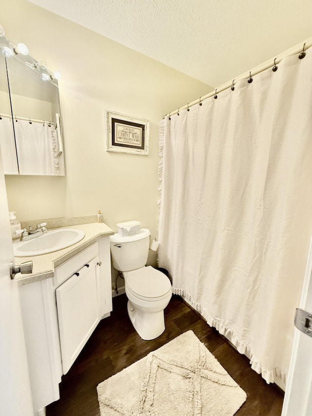 full bathroom with vanity, toilet, wood finished floors, and a textured ceiling