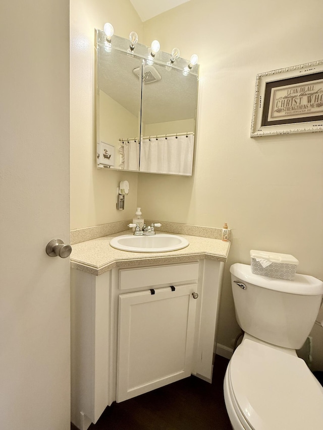 bathroom featuring lofted ceiling, toilet, and vanity