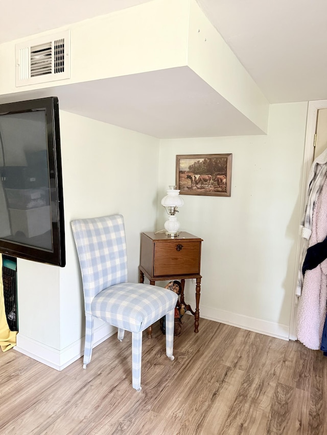 sitting room with wood finished floors, visible vents, and baseboards