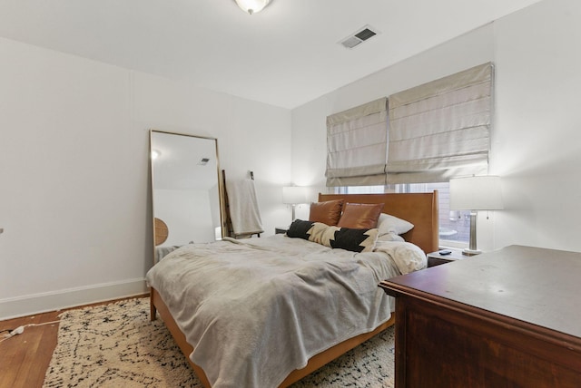 bedroom with visible vents, baseboards, and wood finished floors