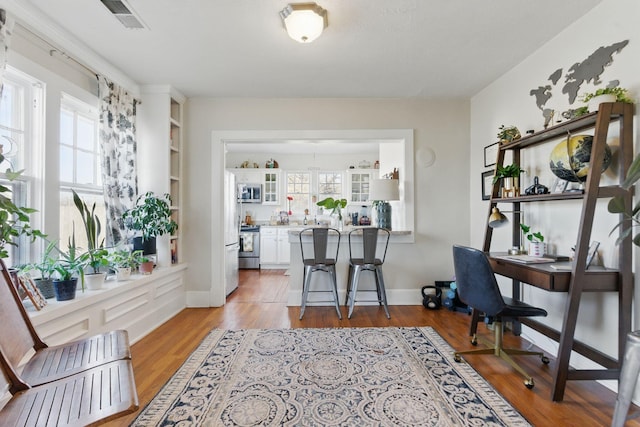 office space with built in features, visible vents, light wood-style flooring, and baseboards