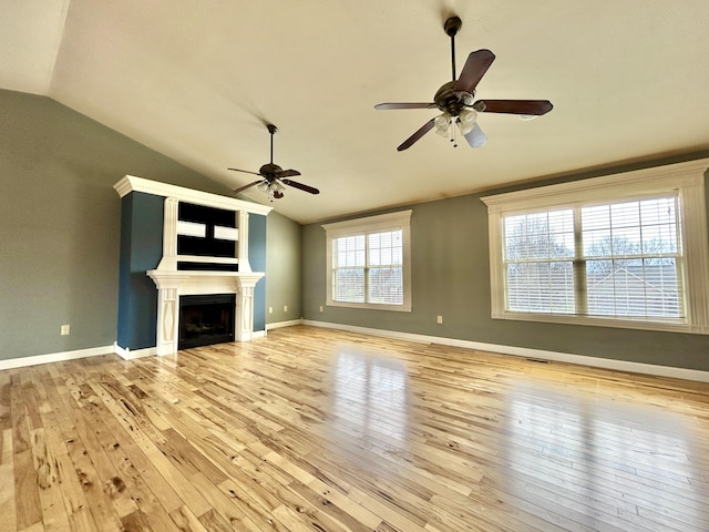 unfurnished living room featuring lofted ceiling, wood-type flooring, a fireplace, and baseboards