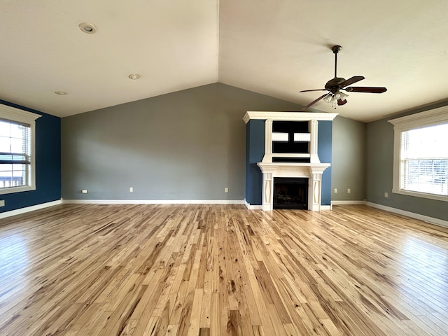 unfurnished living room featuring light wood-style flooring, a fireplace, baseboards, and vaulted ceiling