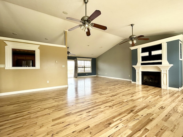 unfurnished living room with a ceiling fan, a large fireplace, vaulted ceiling, wood finished floors, and baseboards