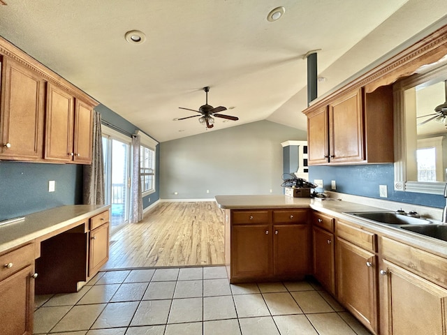 kitchen with vaulted ceiling, ceiling fan, built in desk, and a peninsula