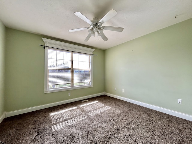 unfurnished room featuring ceiling fan, dark carpet, visible vents, and baseboards