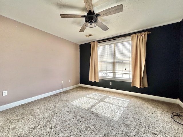 carpeted spare room with ceiling fan, a textured ceiling, visible vents, and baseboards