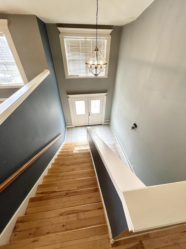 staircase with a chandelier, baseboards, and wood finished floors