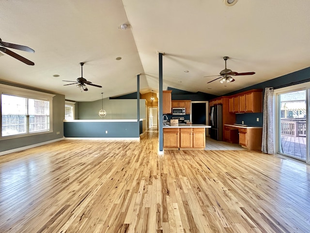 kitchen with light wood finished floors, appliances with stainless steel finishes, open floor plan, light countertops, and a wealth of natural light