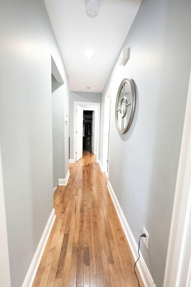 hallway featuring light wood-style flooring and baseboards