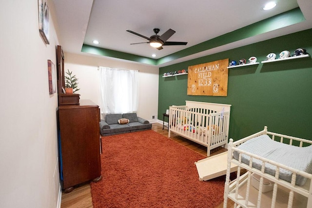 bedroom with recessed lighting, wood finished floors, a ceiling fan, baseboards, and a tray ceiling