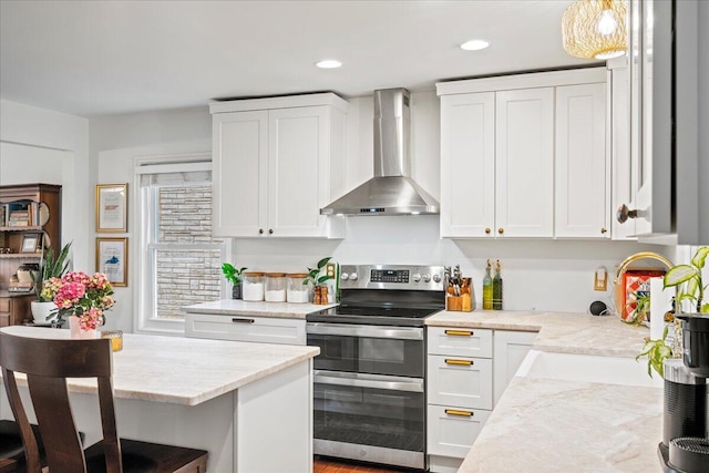 kitchen with wall chimney exhaust hood, double oven range, white cabinets, and a sink