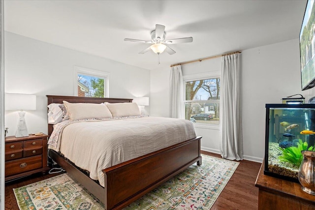 bedroom with multiple windows, wood finished floors, a ceiling fan, and baseboards