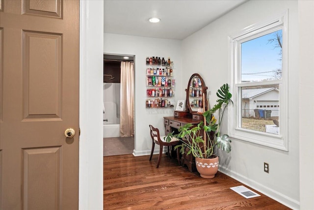 corridor with visible vents, baseboards, and wood finished floors