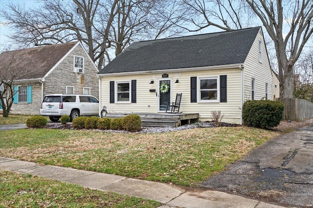 view of front of house featuring roof with shingles and a front yard