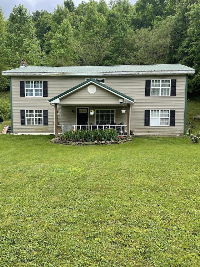 view of front of house featuring covered porch, metal roof, a chimney, and a front yard