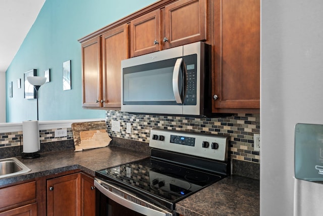 kitchen with appliances with stainless steel finishes, brown cabinetry, dark countertops, and tasteful backsplash