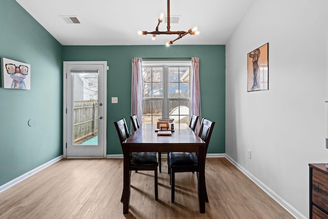 dining space with a chandelier, visible vents, baseboards, and wood finished floors