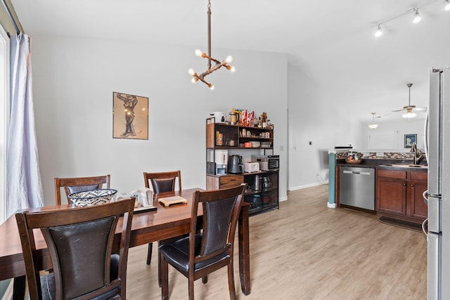 dining area featuring baseboards, vaulted ceiling, light wood-type flooring, track lighting, and ceiling fan with notable chandelier