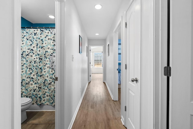 corridor featuring recessed lighting, light wood-style flooring, and baseboards