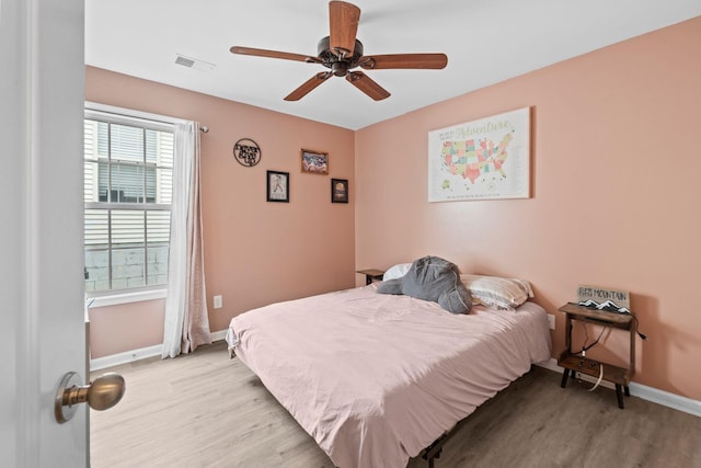 bedroom with baseboards, visible vents, ceiling fan, and light wood finished floors