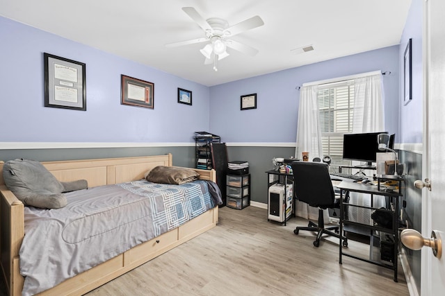 bedroom with a ceiling fan, visible vents, baseboards, and wood finished floors