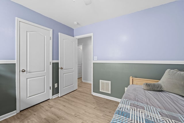 bedroom with wood finished floors, visible vents, and baseboards