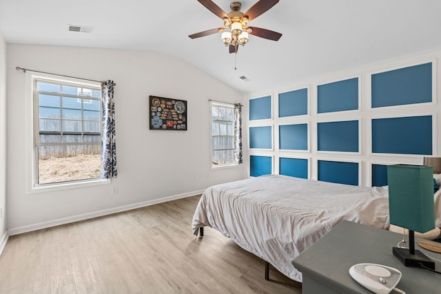 bedroom with lofted ceiling, visible vents, baseboards, and wood finished floors