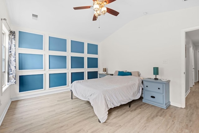 bedroom with vaulted ceiling, light wood finished floors, visible vents, and baseboards