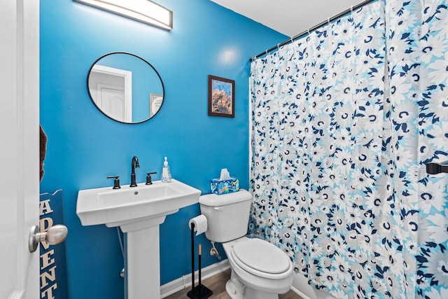 full bath featuring baseboards, toilet, a shower with curtain, wood finished floors, and a sink