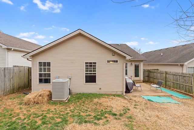 rear view of house with a yard, a fenced backyard, central AC unit, and a patio